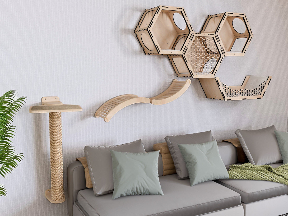 Hexagonal cat wooden shelves and a cat tree on a wall above a gray sofa with cushions.