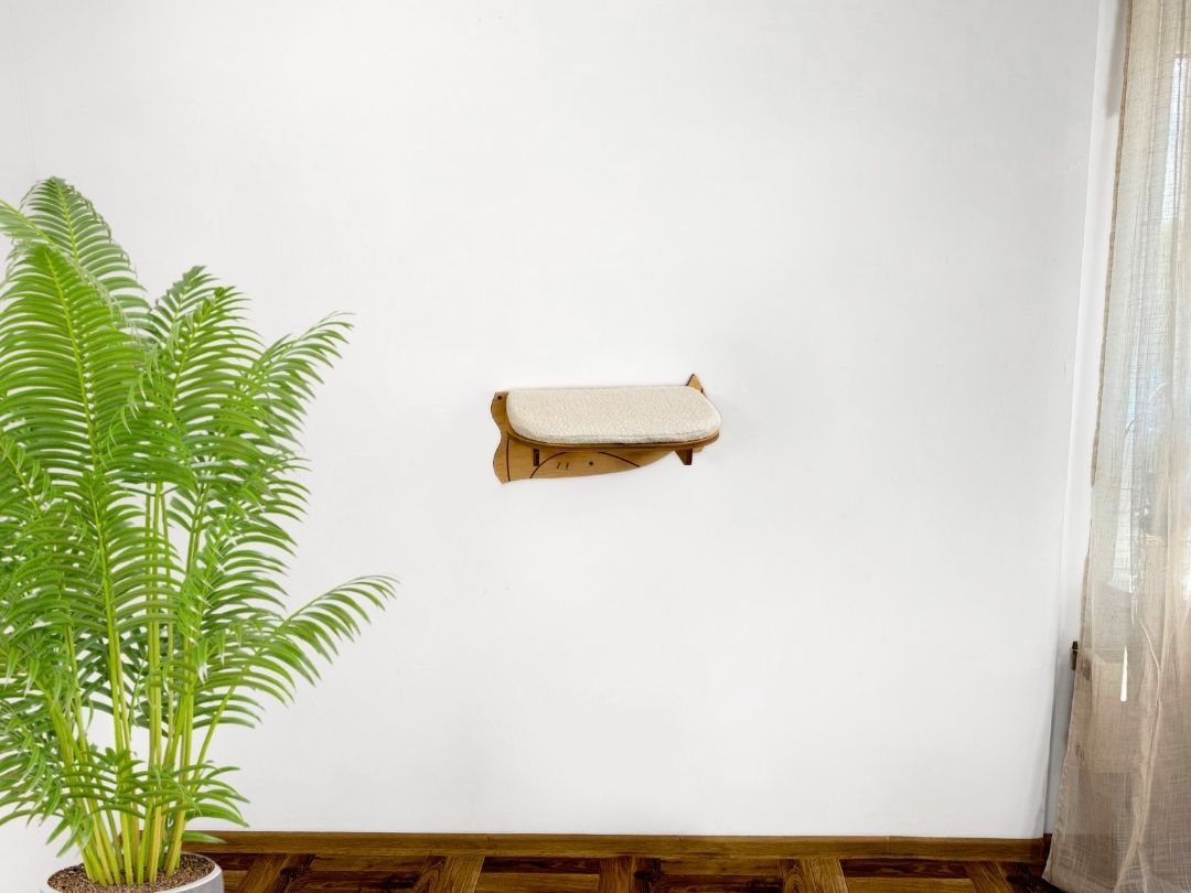 Cat wooden shelf mounted on a white wall next to a potted plant.