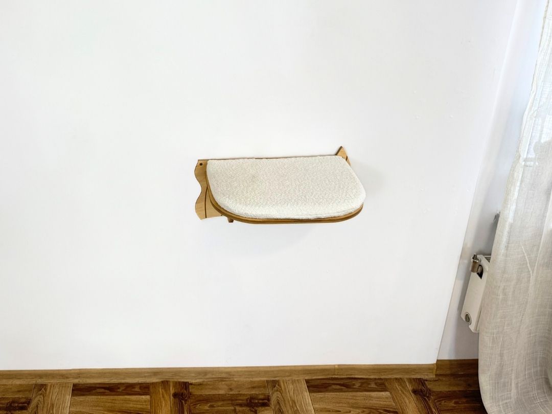 Wall-mounted cat shelf against a white wall with wooden flooring.