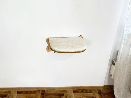 Wall-mounted cat shelf against a white wall with wooden flooring.