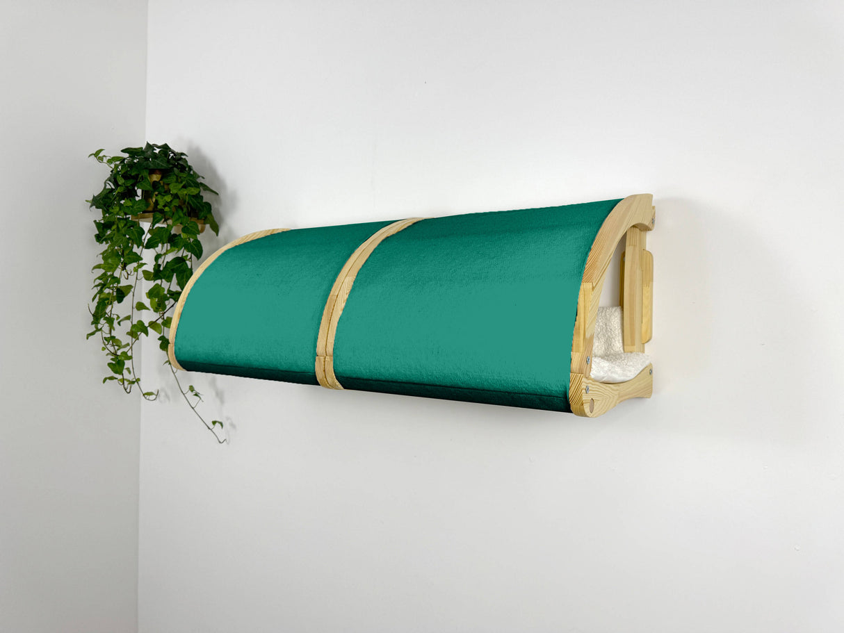 Green pet bed with wooden frame mounted on a white wall