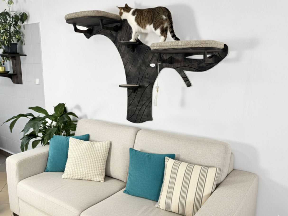 Cat climbing wall attached to a white wall above a beige sofa with blue and patterned cushions.