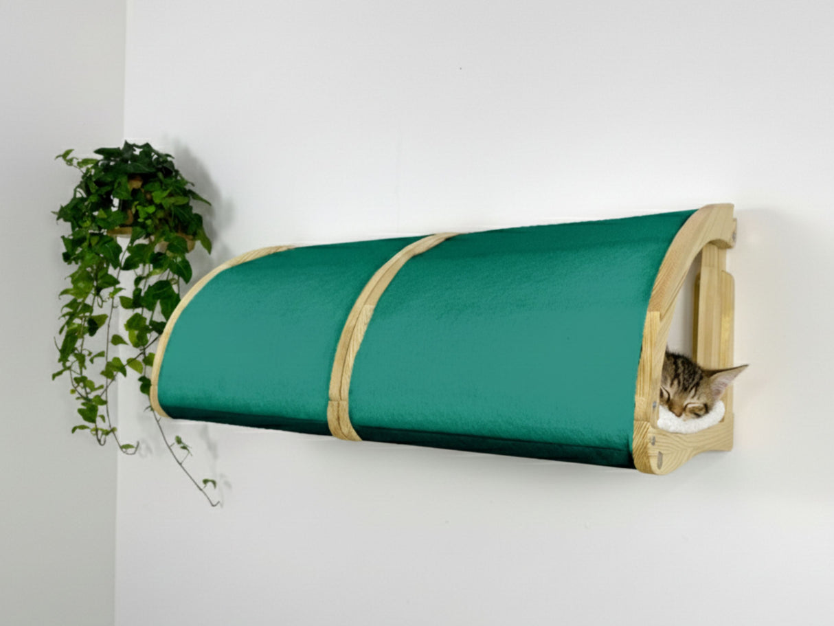 Green cylindrical cat bed with wooden frame against a white wall