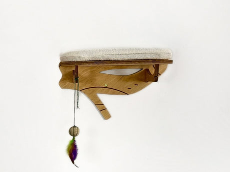 Wooden cat shelf with cushion and feather toy on a white background