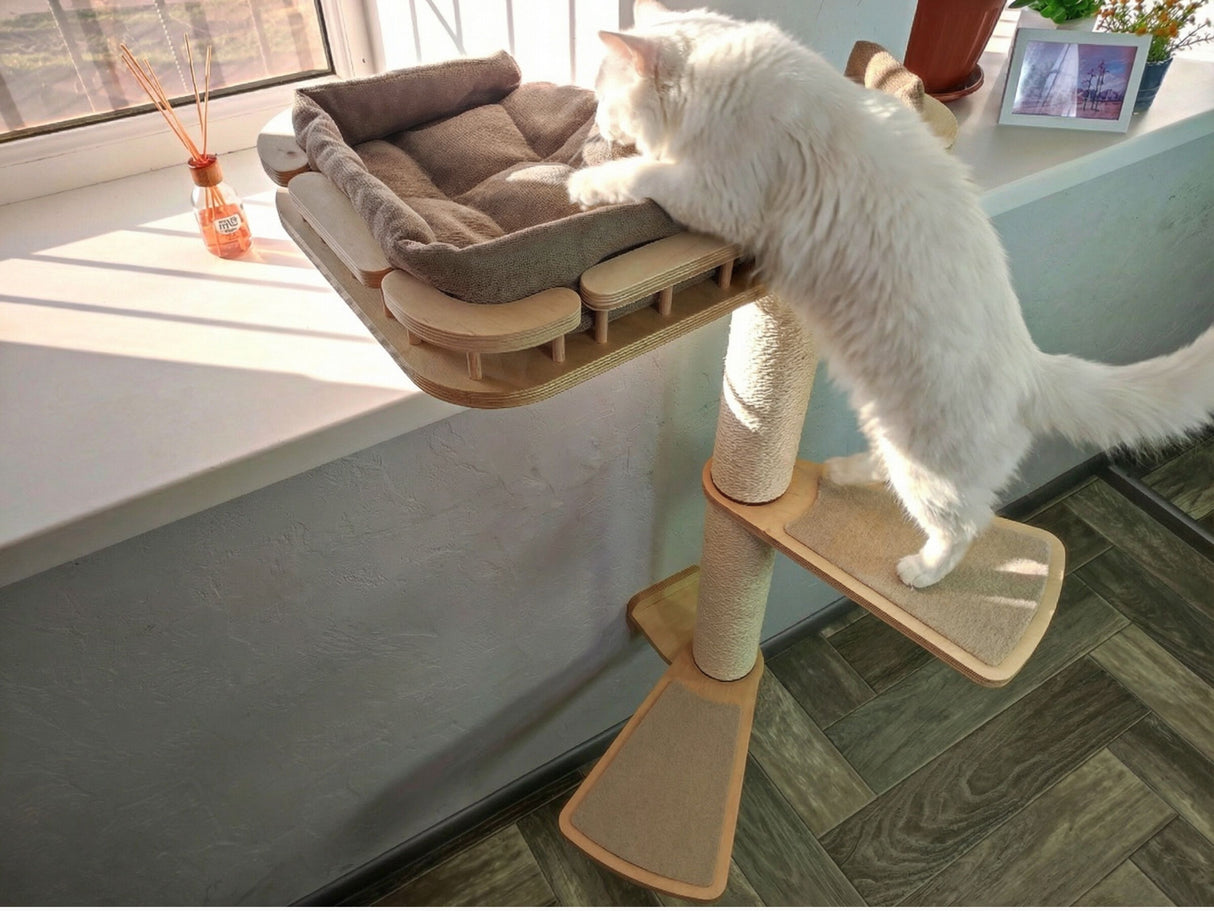 White cat climbing a multi-level cat tree with a cushioned platform.