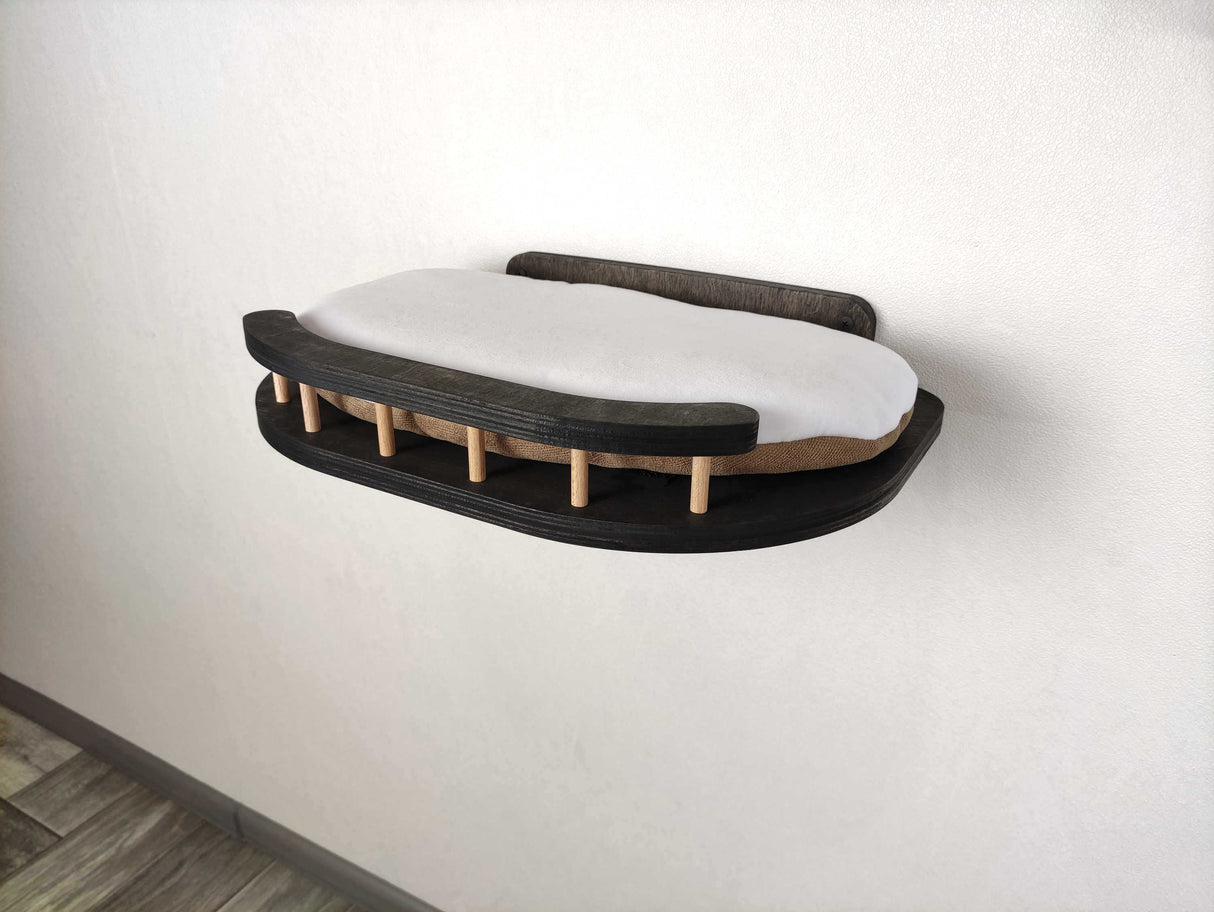 Wall-mounted cat bed with white mattress and wooden slats on a plain wall.