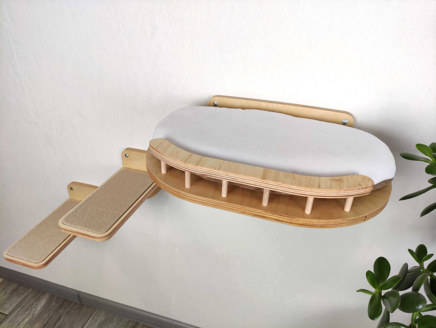 Wooden cat shelf with a white cushion on a light gray wall