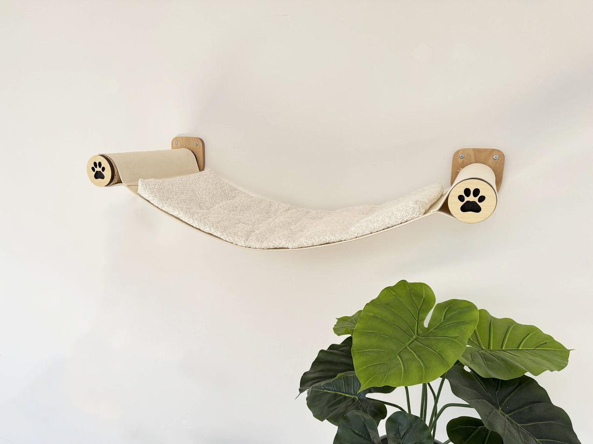 Cat hammock attached to a wall with paw prints on a light background