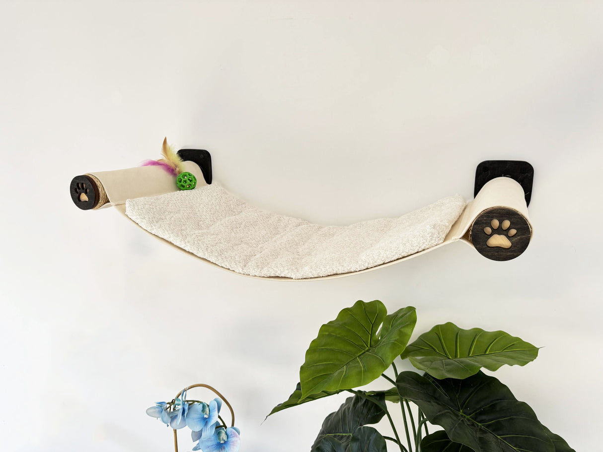 Wall-mounted cat shelf with paw-shaped wheels on a white wall.