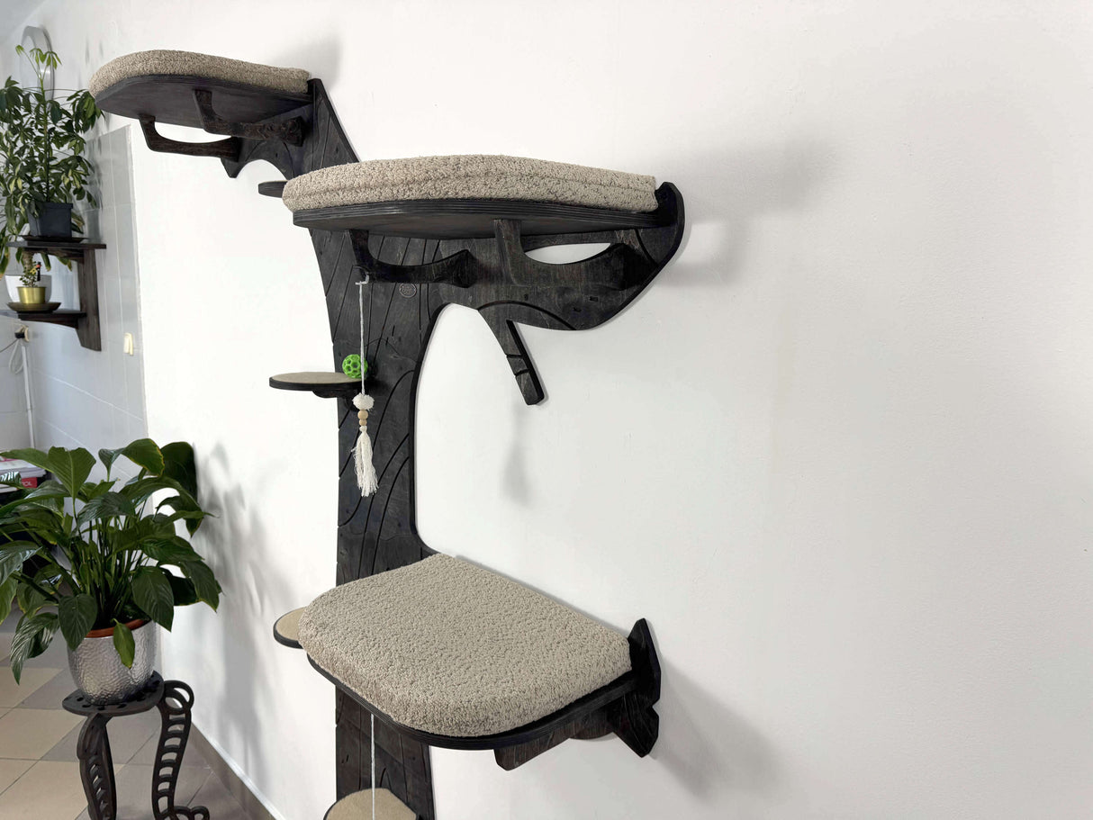 Cat tree with multiple platforms and a hanging toy against a white wall.