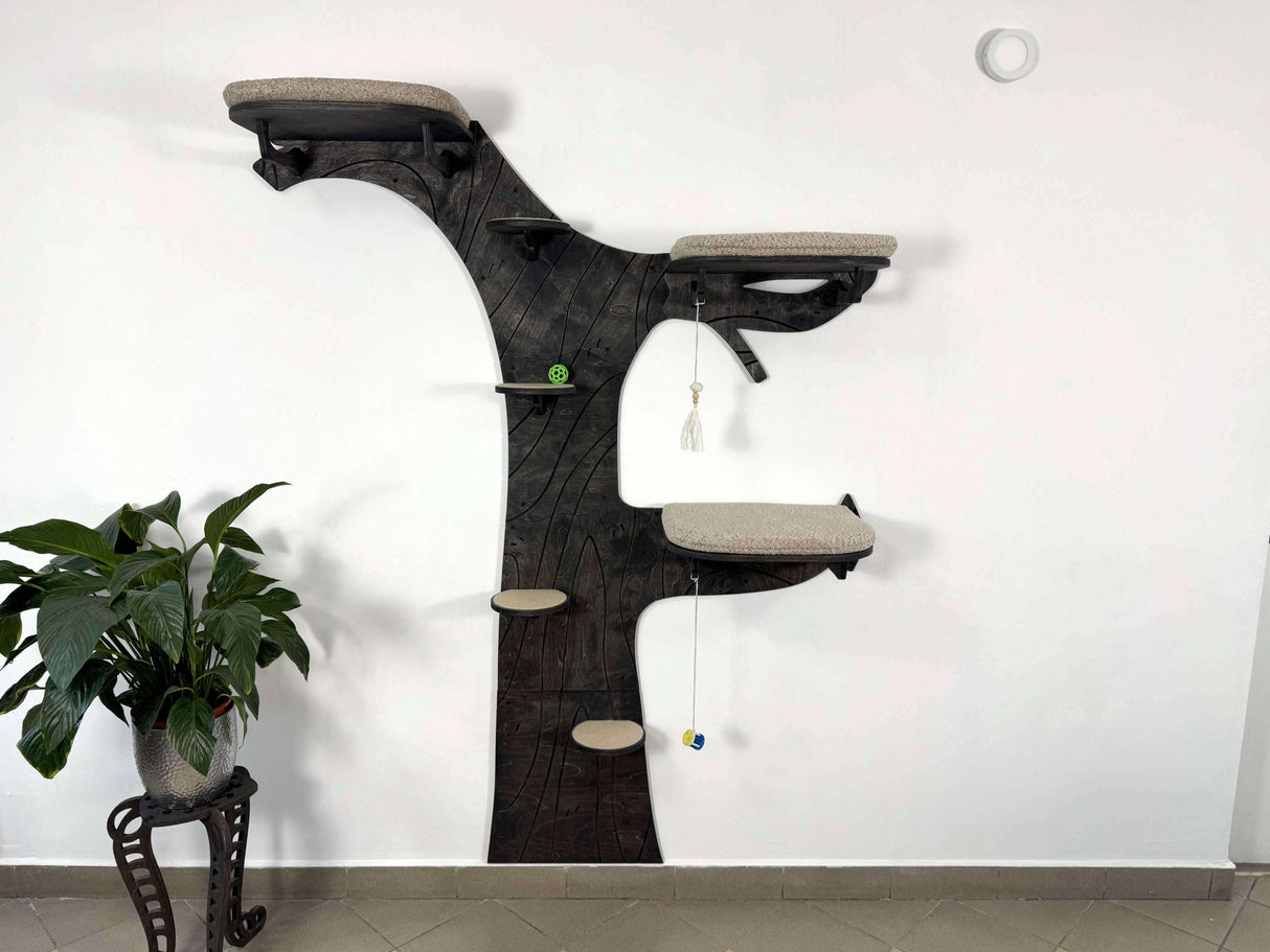 Cat tree designed like a tree with various platforms and toys against a white wall.