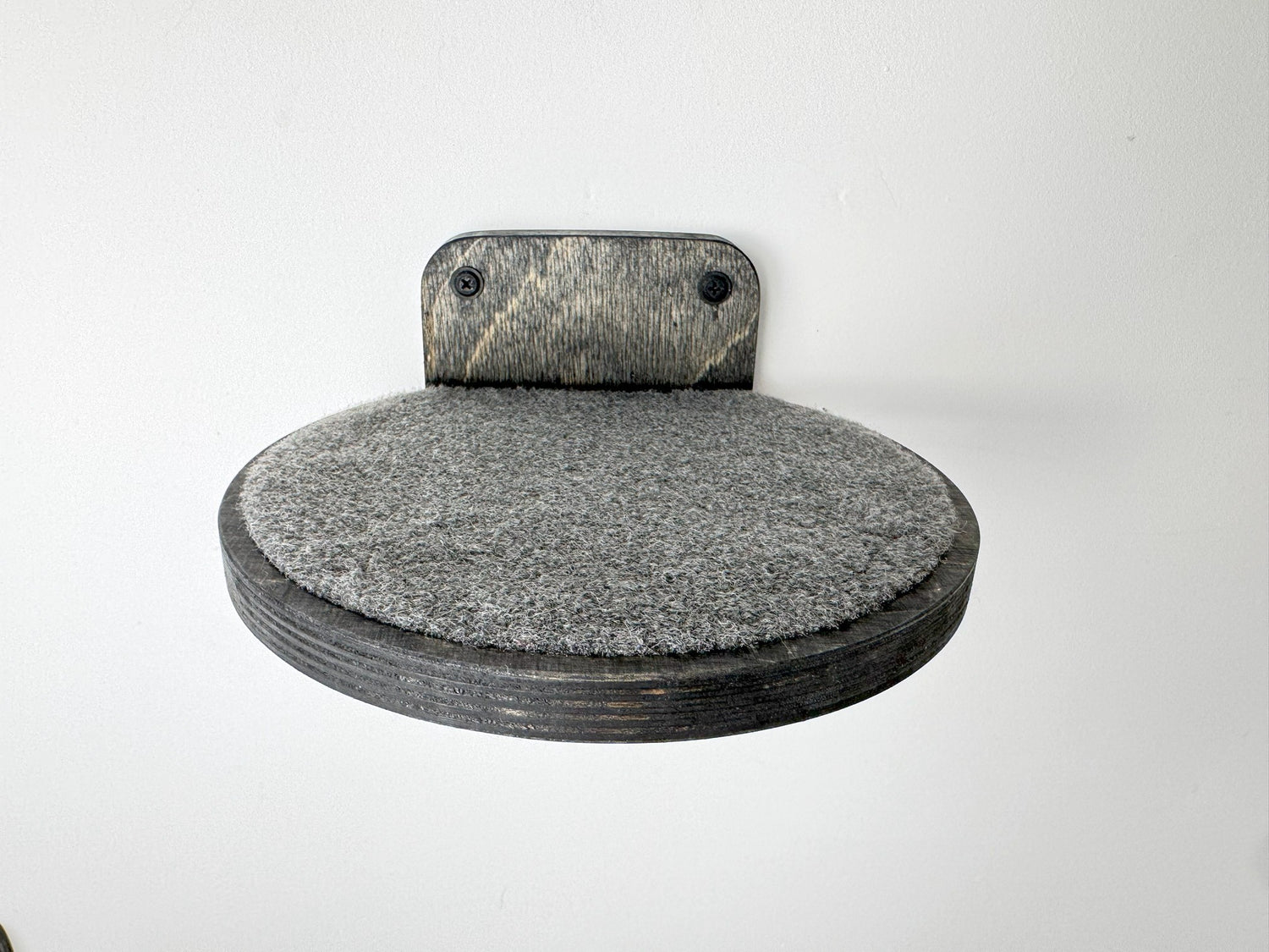 Dark wood round cat wall step with textured carpet, providing a stable climbing surface for felines