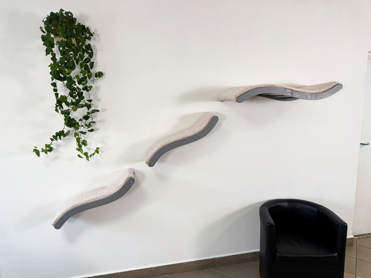 Modern cat tree with curved shelves against a white wall with a plant.
