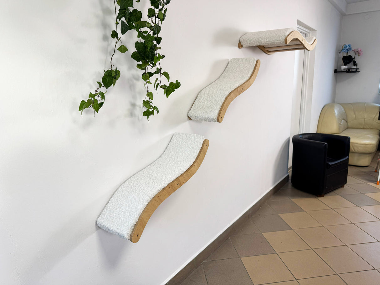 Modern cat tree with multiple levels against a white wall in a room with a plant and furniture.