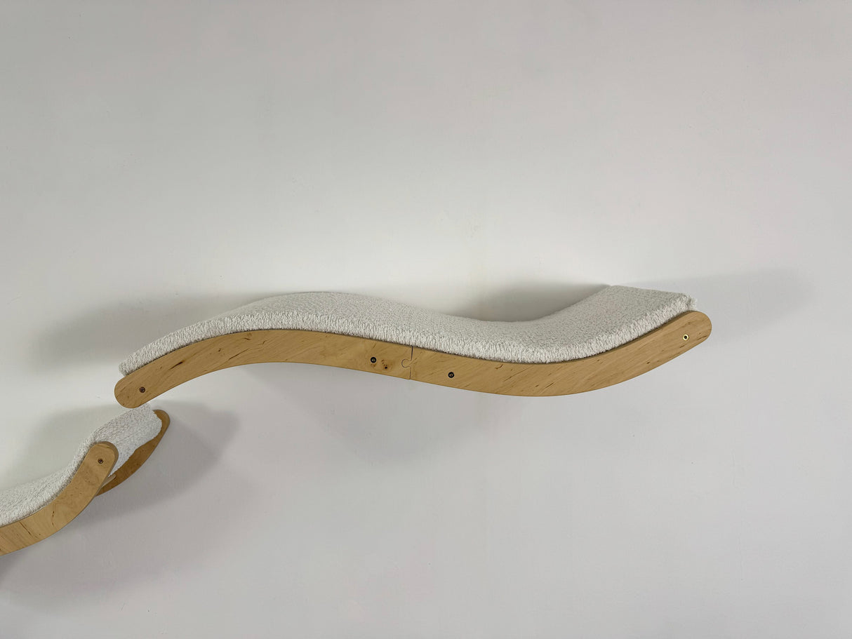 Wavy wooden cat shelf with textured surface on a white background