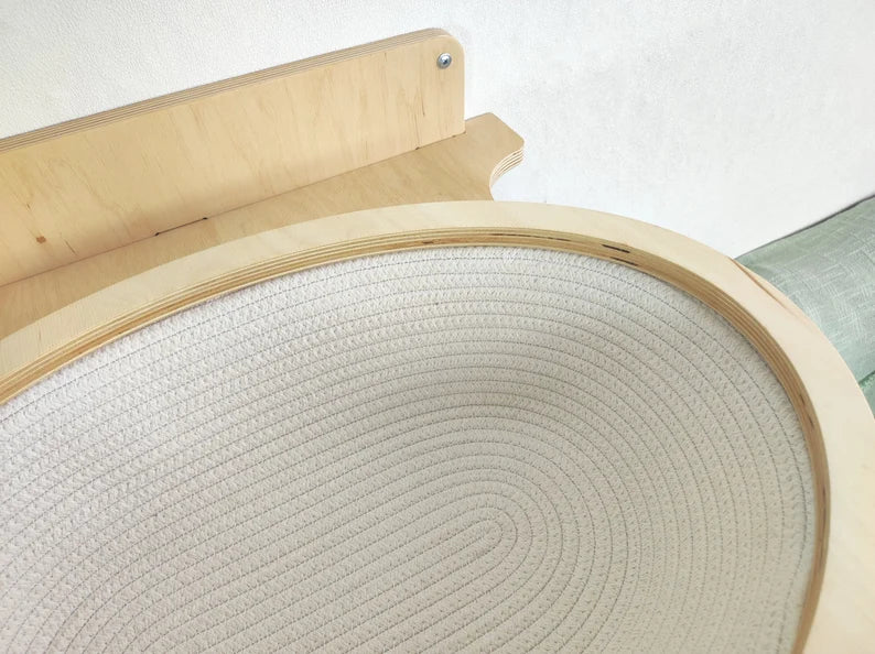 Round wooden pet bed with textured surface on a white background