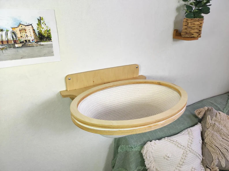 Wooden pet bed attached to a wall in a room with a plant and picture frame.