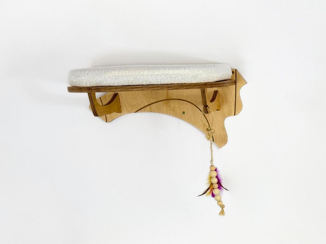 Wooden cat shelf with a cushion and feather toy on a white background