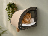 Wall-mounted cat hideout made of dark wood and beige fabric featuring a cat looking out.