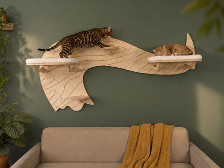 Two cats on a wooden cat shelf against a green wall with a beige sofa and yellow blanket.