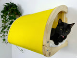 Black cat inside a yellow and wooden pet bed on a white background