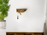 Wooden cat shelf with a white stone top against a white wall, next to a potted plant.