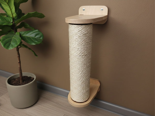 Cat scratching post against a brown wall with a plant on a wooden floor.