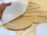 Hand holding a white towel over a wooden product with a white background