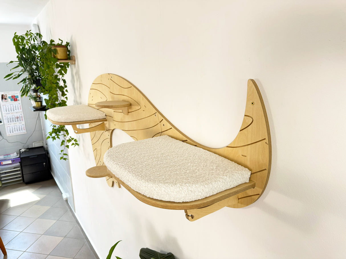 Wooden wall-mounted cat shelf with a cushion in a room setting.