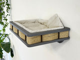 Wall-mounted pet bed with wicker sides and soft cushion on a white wall.