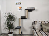 Cat tree with platforms and a plant in a room with a sofa and cushions.