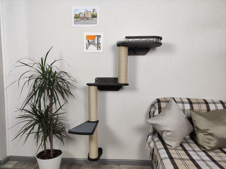 Cat tree with platforms and a plant in a room with a sofa and cushions.