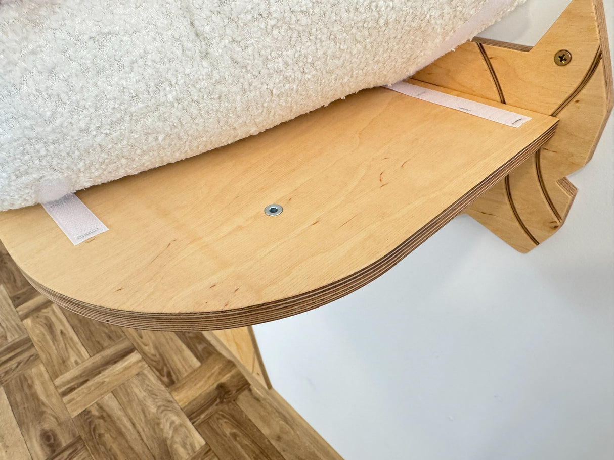 Wooden cat shelf with a textured white surface on top against a light background