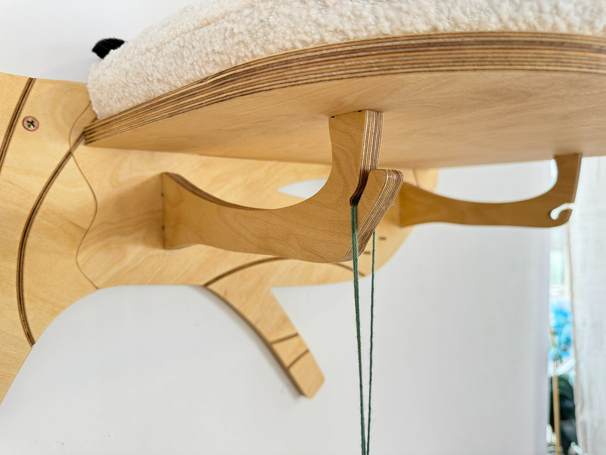 Wooden cat tree with a cushioned platform and perches on a white background