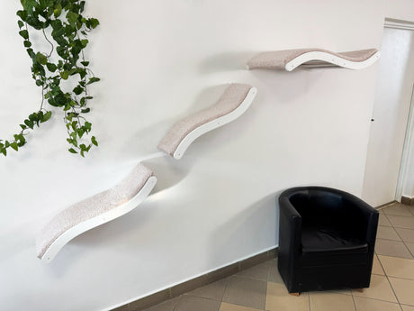 Modern cat tree with a black chair against a white wall