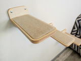 Wooden cat shelf attached to a wall with a striped blanket in the background.