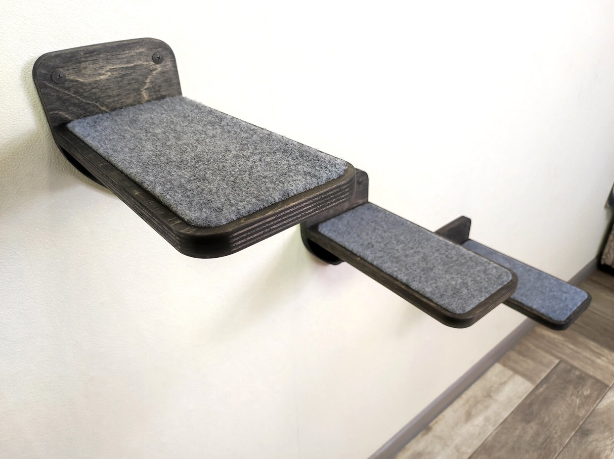 Wooden pet platform with gray cushion on a light wooden floor.