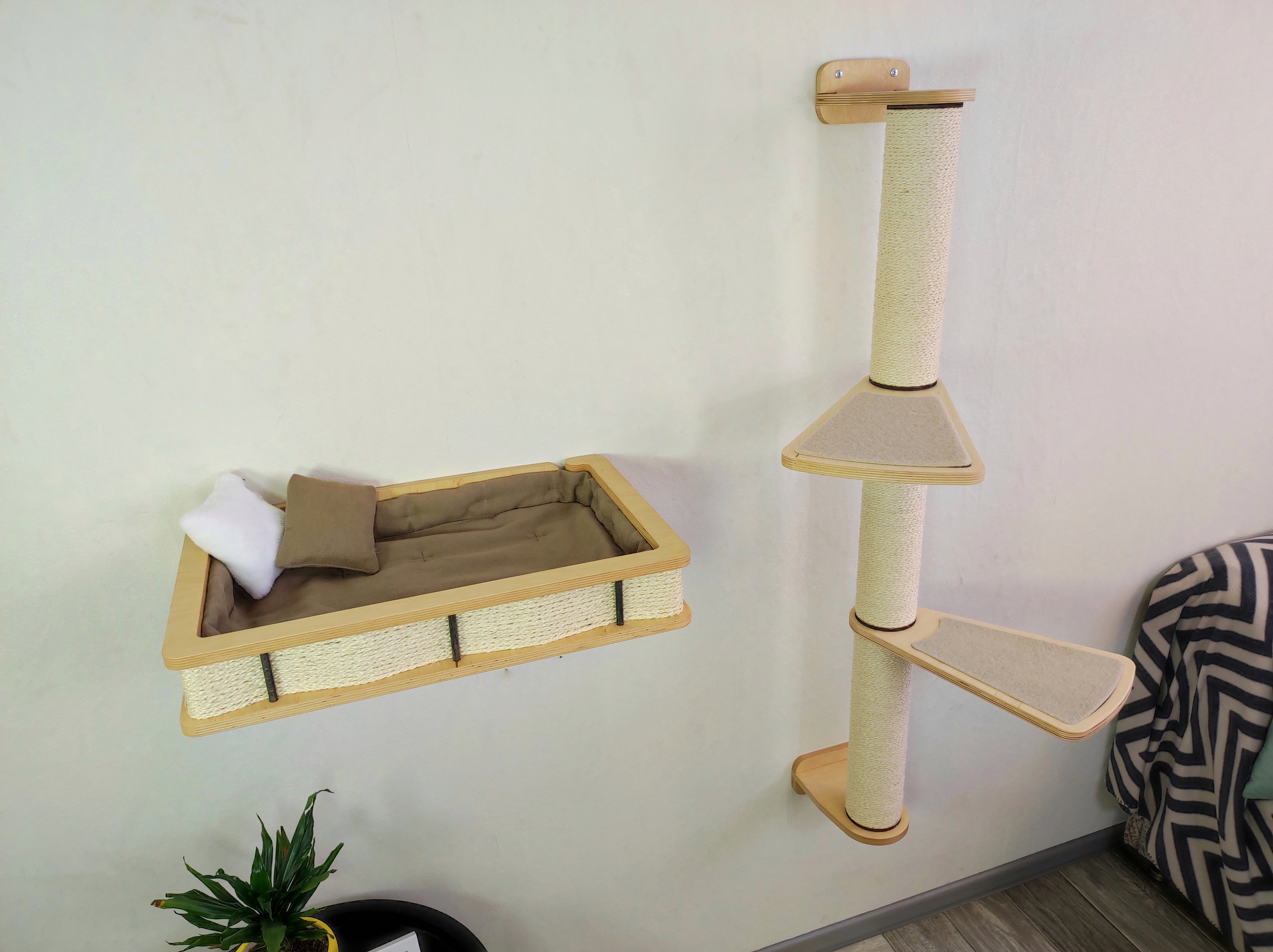 A set of wall-mounted cat furniture, a large shelf with a soft cushion and a vertical scratching post with steps to make it convenient for the cat to climb onto the bed